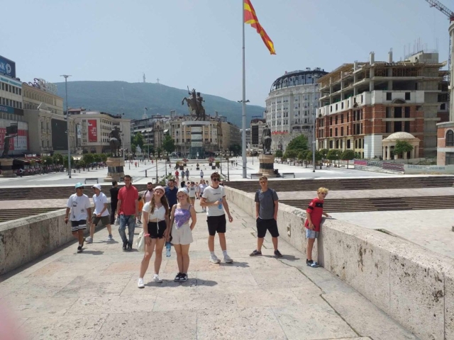 młodzież stojąca na kamiennym moście, w tle główny plac miasta Skopje