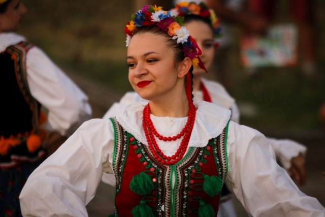 tancerka zespołu Kalina z wiankiem na głowie i koralami na szyi, w białej koszuli uśmiechająca się