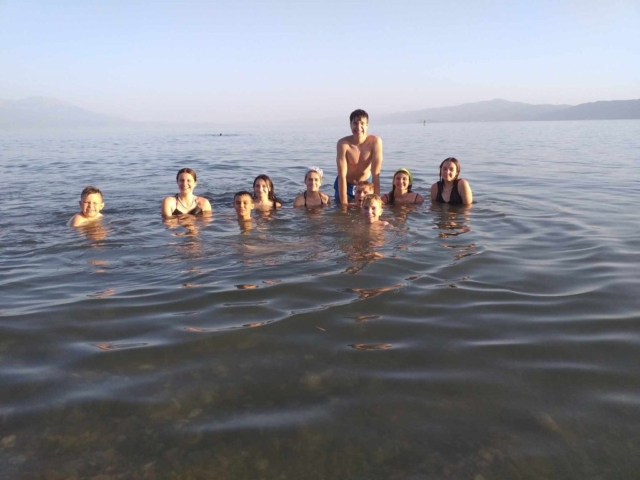 Grupa młodzieży stojąca w wodzie jeziora i pozująca do zdjęcia