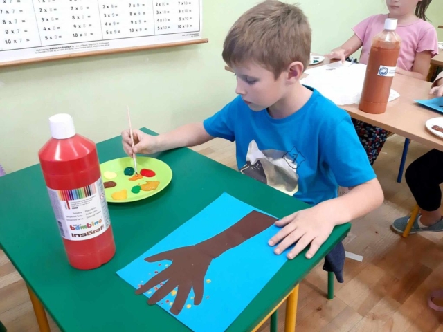 Uczeń za pomocą pędzelka i farbek wykonuje pracę plastyczną