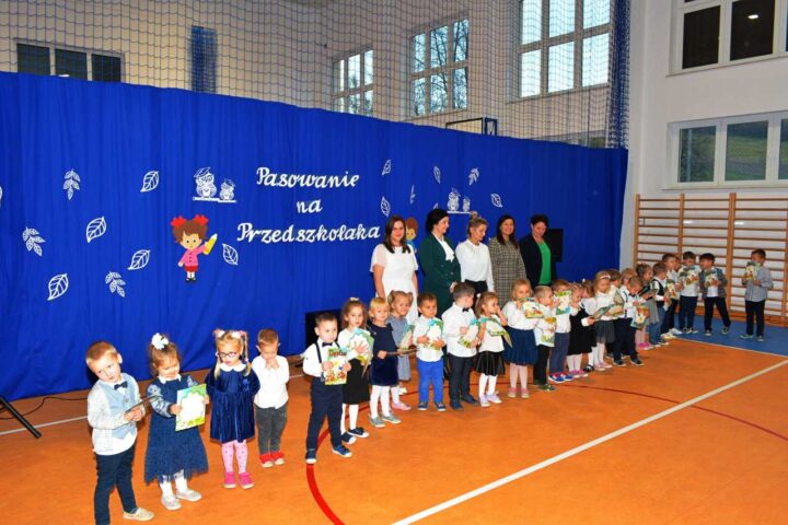 Dzieci pasowane na przedszkola pozują do zdjęć trzymając dyplomy. Za nimi panie wychowawczynie, pani Dyrektor oraz Wójt Gminy Dydnia.