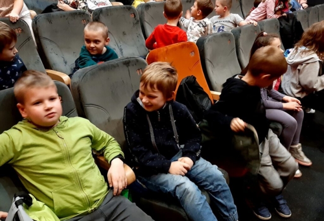 Uczniowie siedzą na widowni w oczekiwaniu na przedstawienie