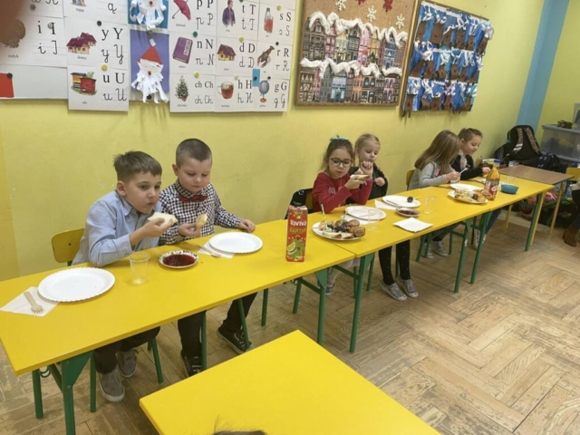 Spotkanie wigilijne klasy I . Uczniowie częstują się świątecznym jedzeniem