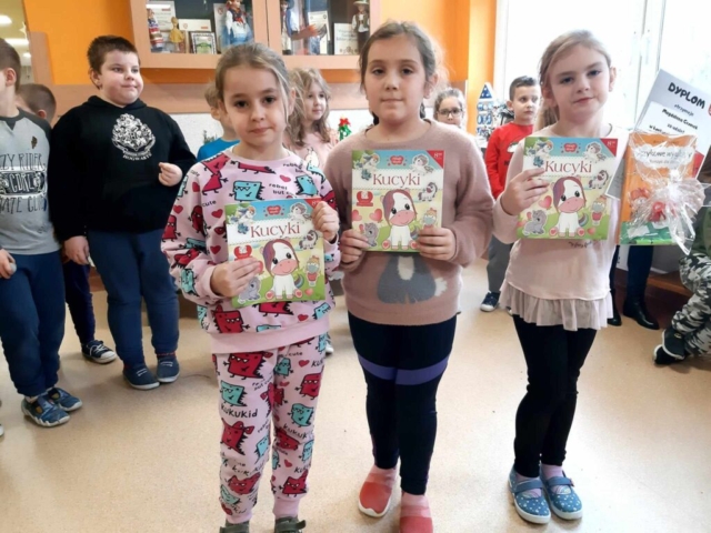 Trzy dziewczynki prezentują nagrody zdobyte w konkursie czytelniczym