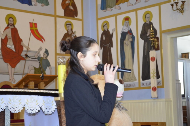 Dziewczynka stoi z mikrofonem i śpiewa kolędę, w tle wnętrze kościoła