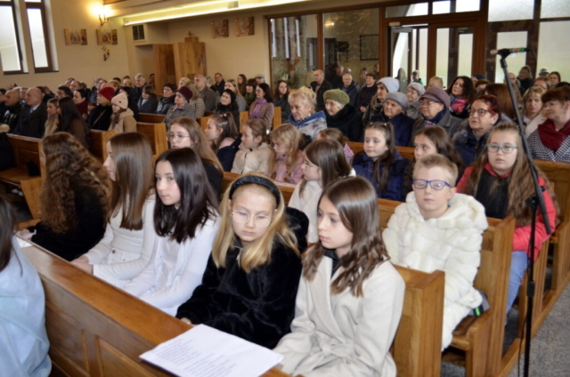 Dzieci występujące i publiczność siedzi na kościele
