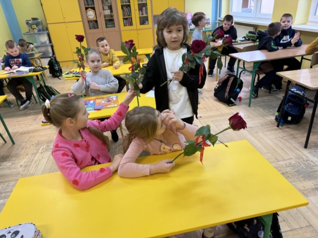Chłopiec wręcza dziewczynce czerwoną różę z okazji Walentynek w klasie szkolnej
