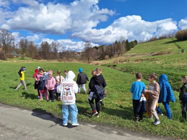 Dzieci wesoło bawią się na trawie podczas wiosennej przechadzki