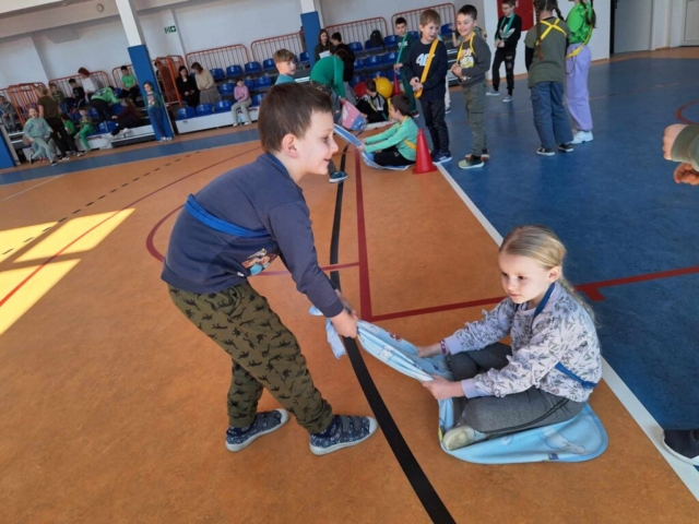 Uczeń ciągnie dziewczynkę na kocu w ramach jednej z konkurencji na turnieju
