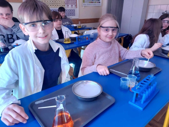 Dzieci wykonują doświadczenia chemiczne pod kontrolą osoby prowadzącej i nauczycieli