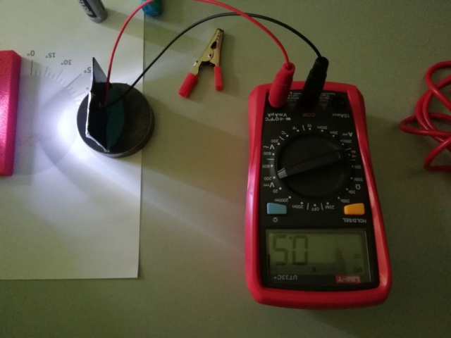 Na stole leży zestaw pomiarowy do mierzenia natężenia prądu powstającego ze światła padającego na panel fotowoltaiczny
