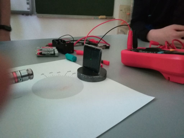 Uczeń świeci zielonym laserem na panel fotowoltaiczny aby sprawdzić, czy wytworzy się prąd